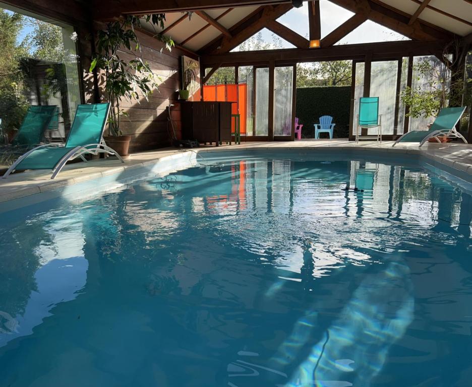 une piscine avec deux chaises et une table dans l'établissement Maison avec piscine et sauna à Vire, à Vire