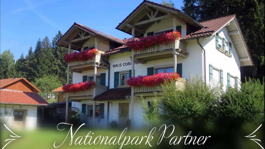 a white building with red flowers on it at Ferienhaus Corinna in Kirchdorf im Wald