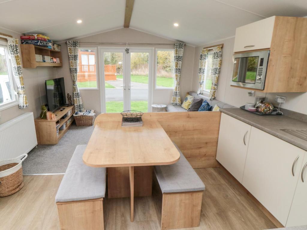 a kitchen with a wooden table and benches in a caravan at Pines 30 in Scarborough