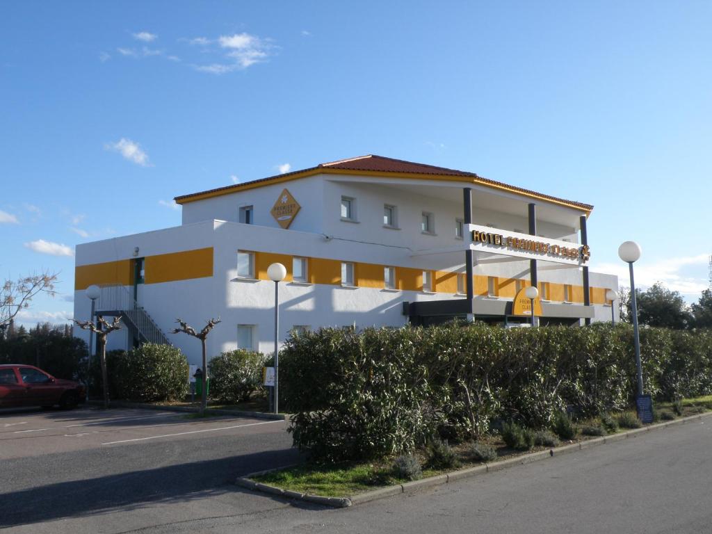 a white building with a sign on it next to a street at Première Classe Perpignan Nord in Rivesaltes