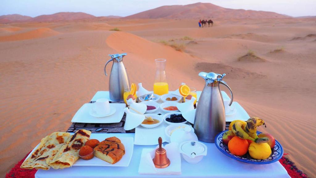 a table with food and drinks in the desert at Authentic Desert Luxury Camp in Merzouga