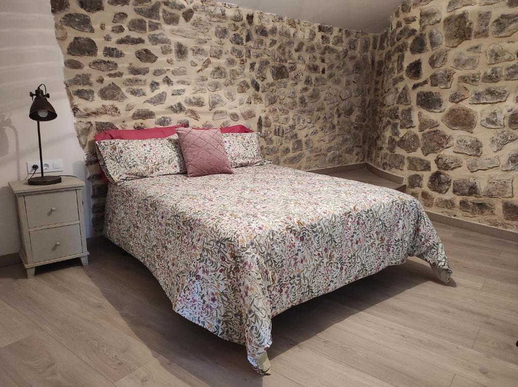 a bedroom with a bed and a stone wall at Casa el Recreo in Jérica