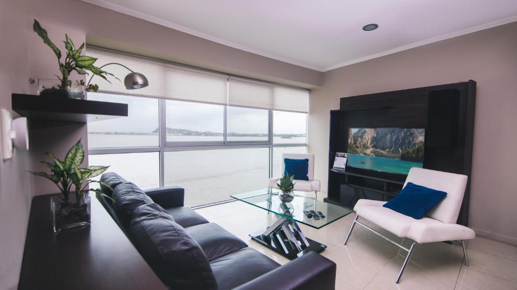 sala de estar con sofá y TV en Riverfront I 1, piso 4, suite vista al rio, Puerto Santa Ana, Guayaquil, en Guayaquil