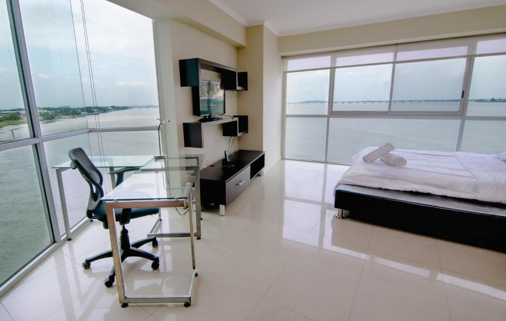 1 dormitorio con escritorio, 1 cama y mesa de cristal en Riverfront I 2, piso 4, suite vista al rio, Puerto Santa Ana, Guayaquil, en Guayaquil
