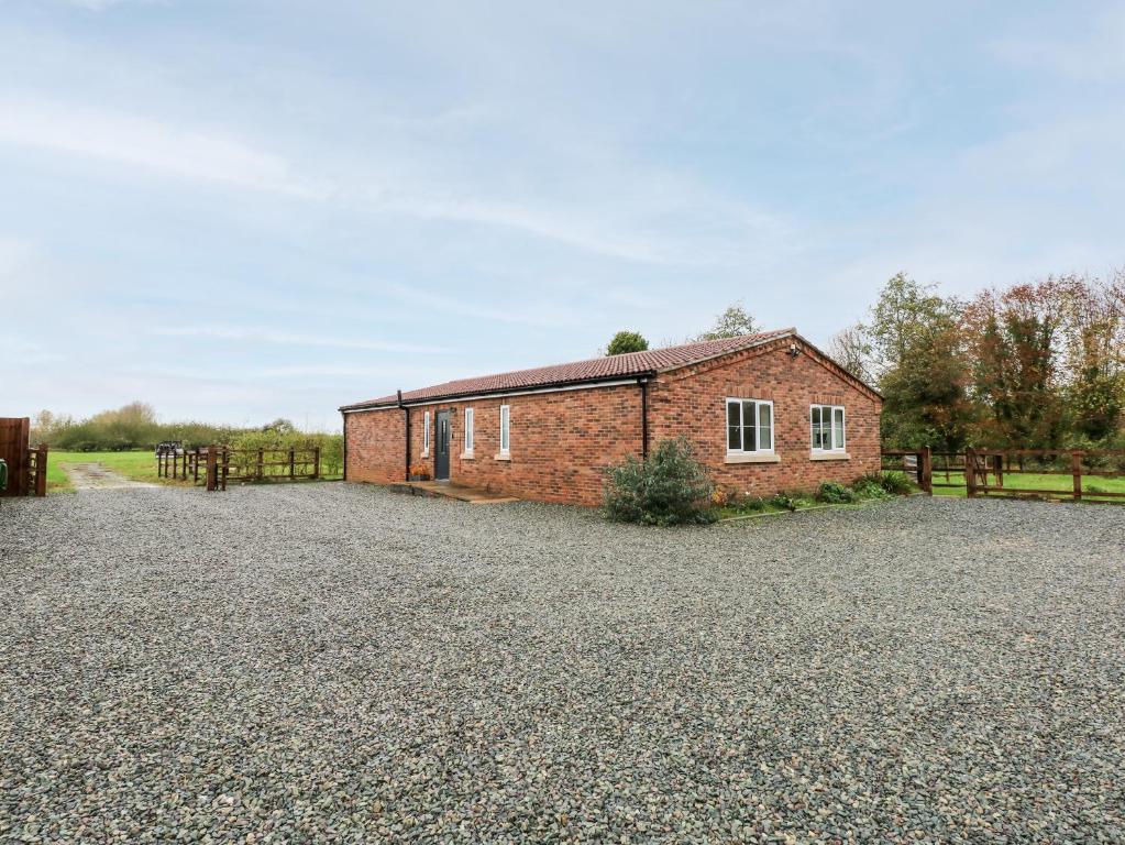 a red brick building on a gravel driveway at The Apple Shed in Wisbech