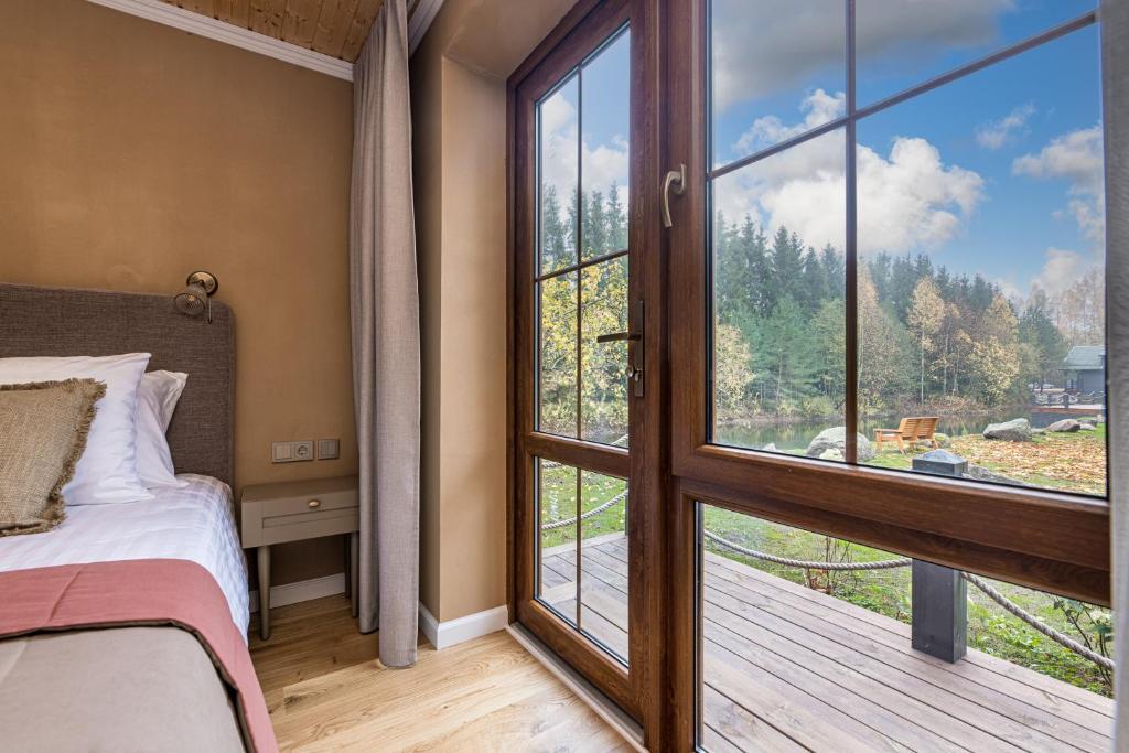 a bedroom with a bed and a large window at Želvė Village & SPA 