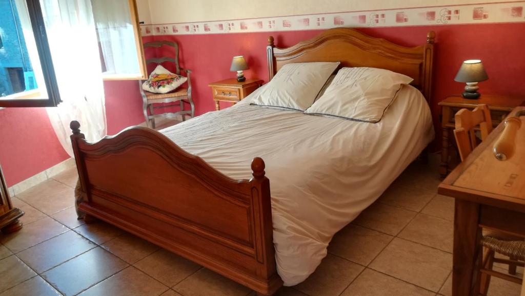 ein Schlafzimmer mit einem großen Bett mit einem Holzrahmen in der Unterkunft Gîte du Pressoir in Cerdon