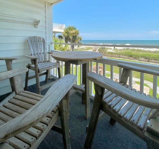 two wooden benches and a table and chairs on a porch at Boston Commons 101 Condo in Myrtle Beach
