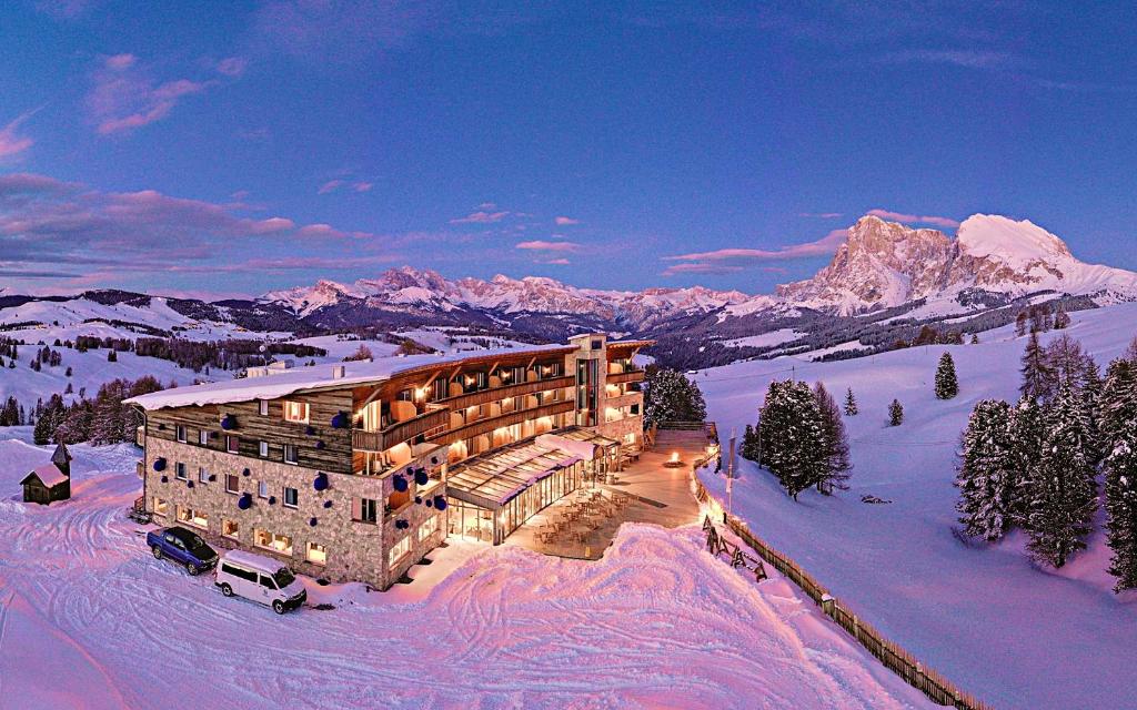 a large building in the snow in the mountains at Paradiso Pure Living Vegetarian-Vegan Hotel in Alpe di Siusi