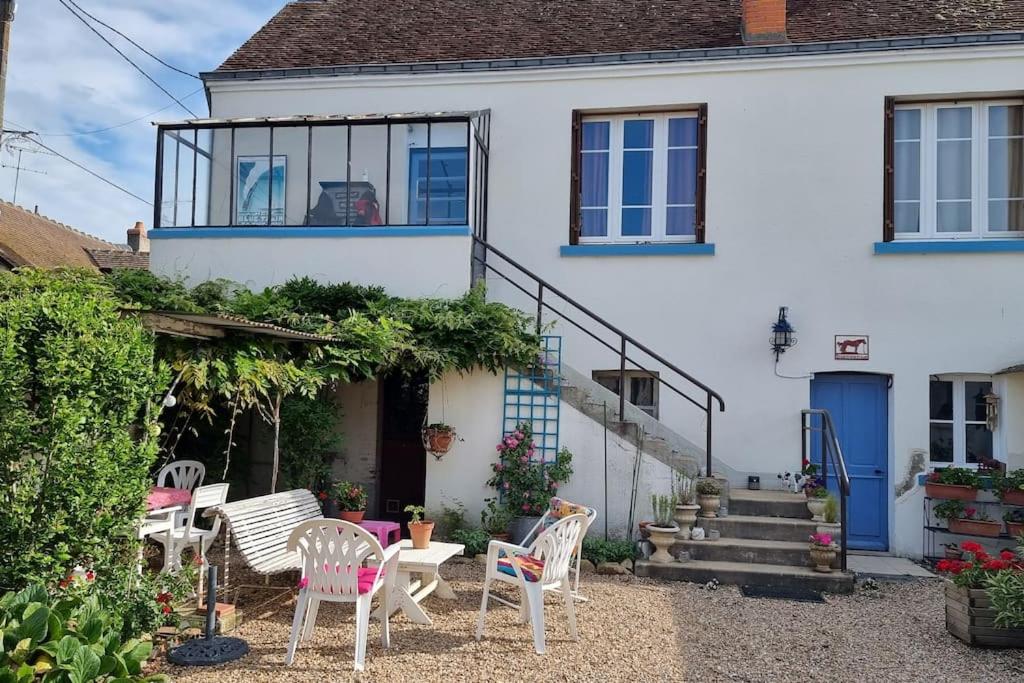 a house with chairs and tables in front of it at Les Noyers Monestois entre Cher et Canal de Berry in Mennetou-sur-Cher