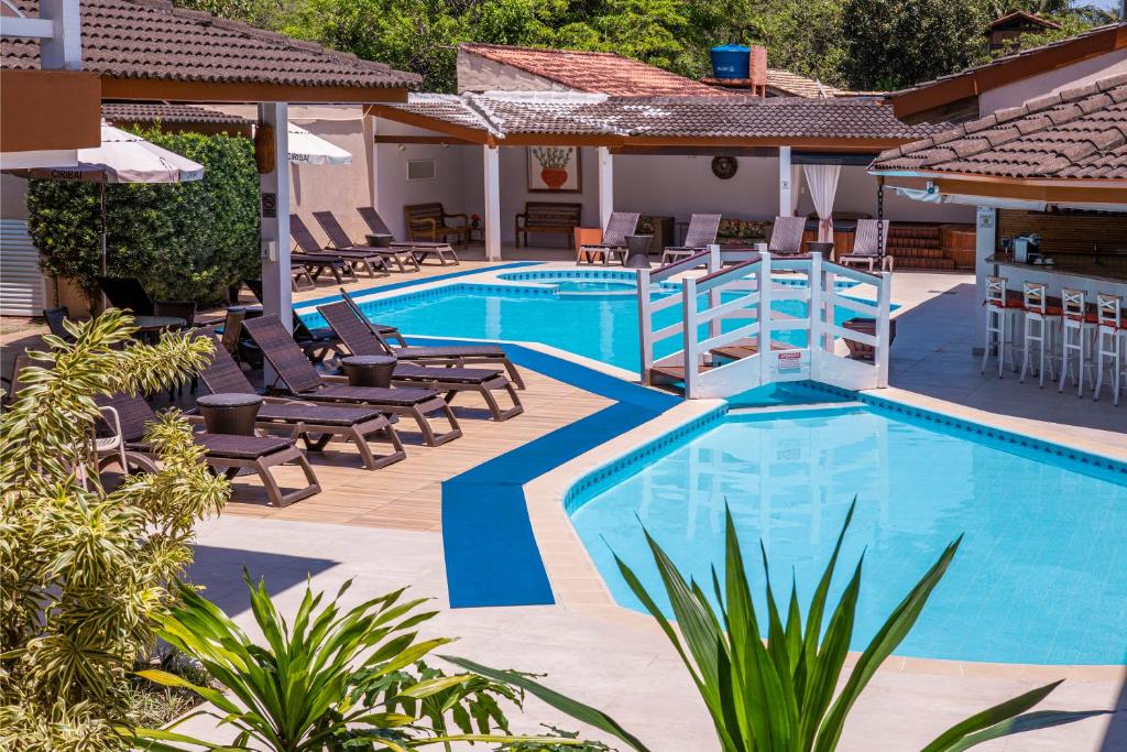 einen Pool in einem Hotel mit Liegestühlen und Tischen in der Unterkunft Ciribaí Praia Hotel in Pauba