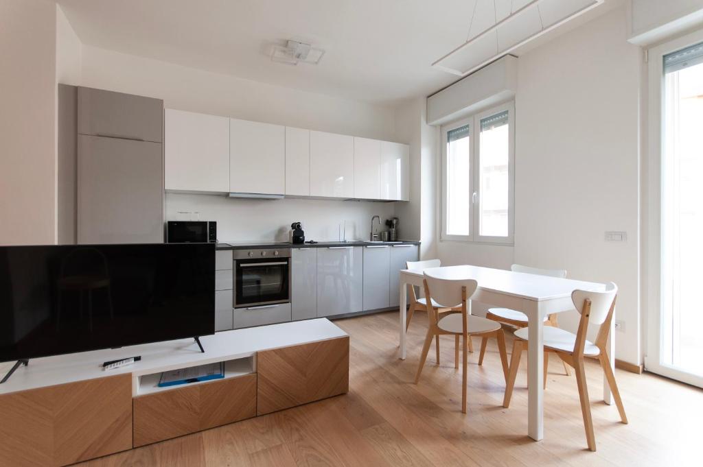 Il comprend une cuisine blanche avec une table et des chaises ainsi qu'une télévision. dans l'établissement YouHosty - Del Castagno 2, à Milan