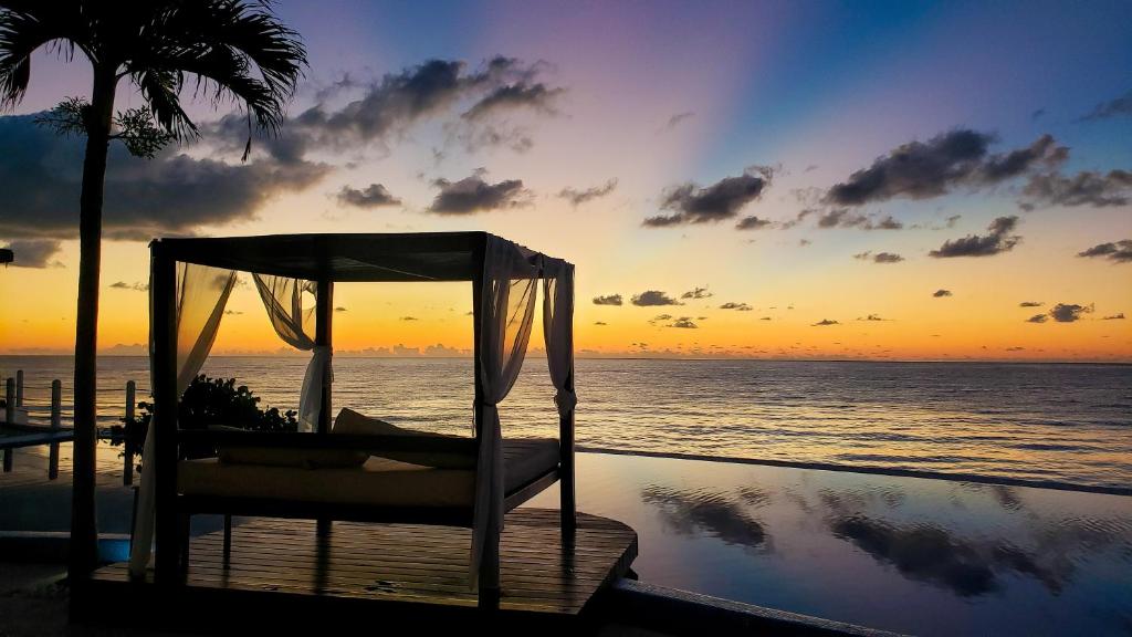 Cama en la playa con puesta de sol en el fondo en Senses Riviera Maya - Oceanfront All inclusive Boutique hotel - Adults only, en Puerto Morelos