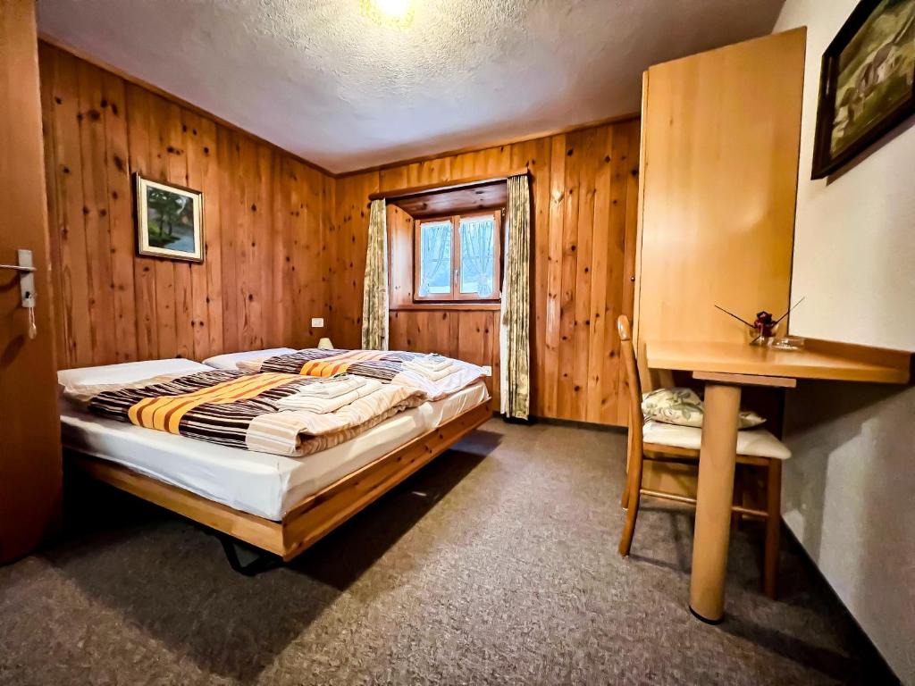 a bedroom with a bed and a wooden wall at Albergo Ristorante Selva in Poschiavo