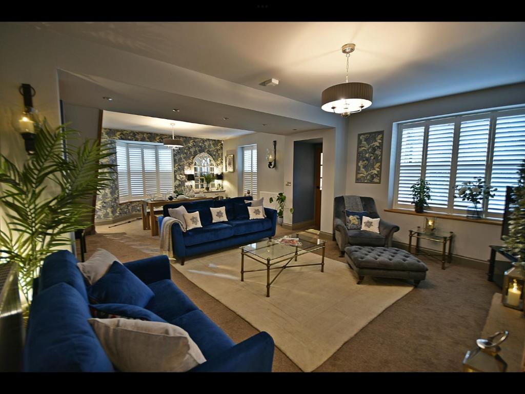 a living room with blue couches and a dining room at Luxury Waddington Cottage, Ribble Valley in Waddington