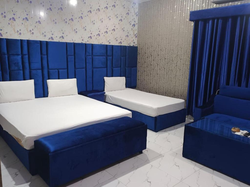una camera con due letti e un divano blu di Hotel Sereena residence a Multan
