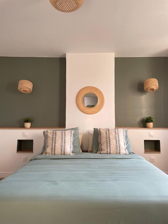 een slaapkamer met een groot bed met blauwe lakens en kussens bij L'Appartement Vert in Douai