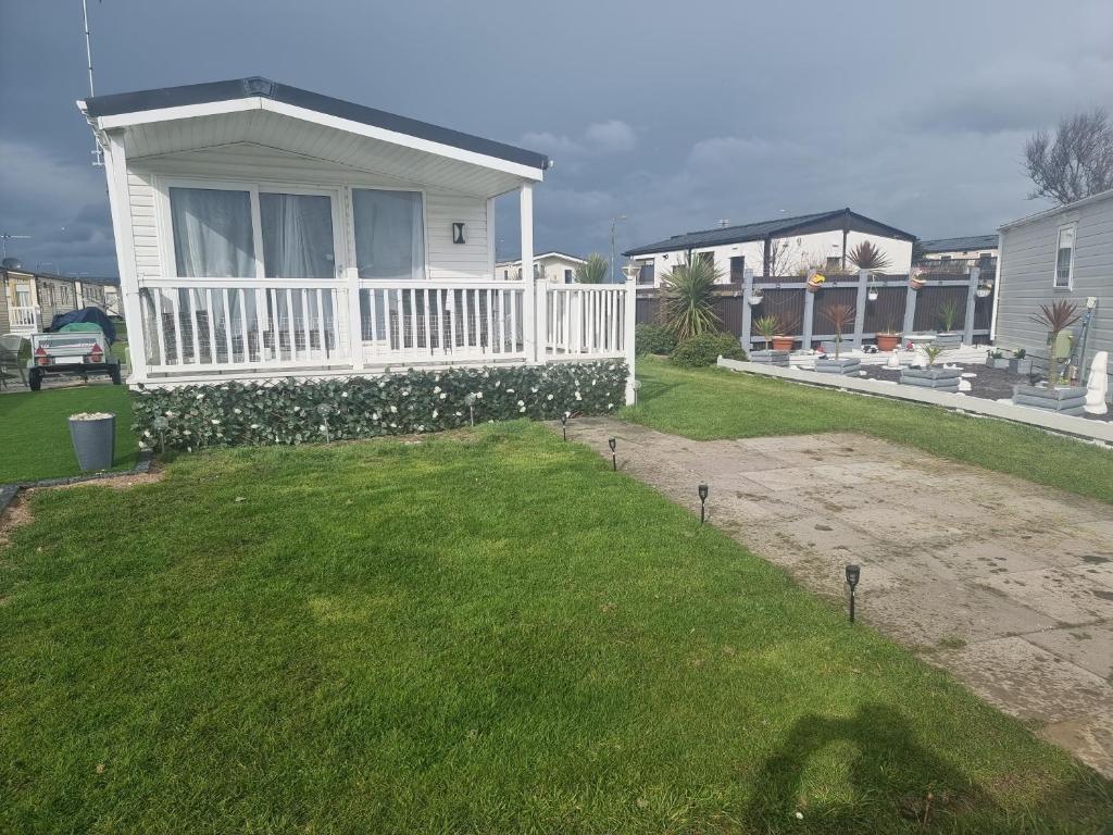 a yard with a white fence and a house at Lyons robin hood lodge Rhyl in Rhyl
