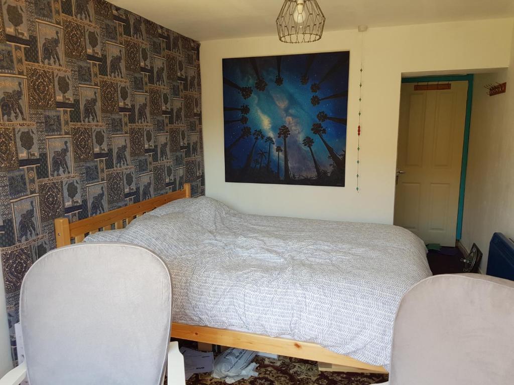a bedroom with a bed and two chairs at Garden room in Exmouth