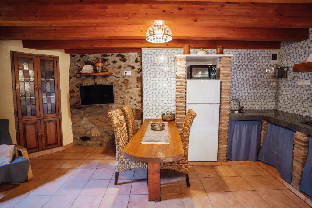 a kitchen with a wooden table and a refrigerator at Casa Rural El Callís in Vall de Bianya