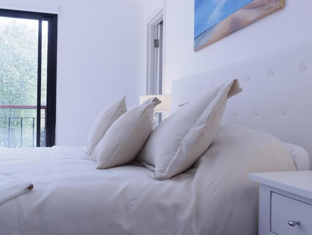 a white bed with white pillows on top of it at B Excepcional monoambiente en Mar del Plata a metros del mar in Mar del Plata