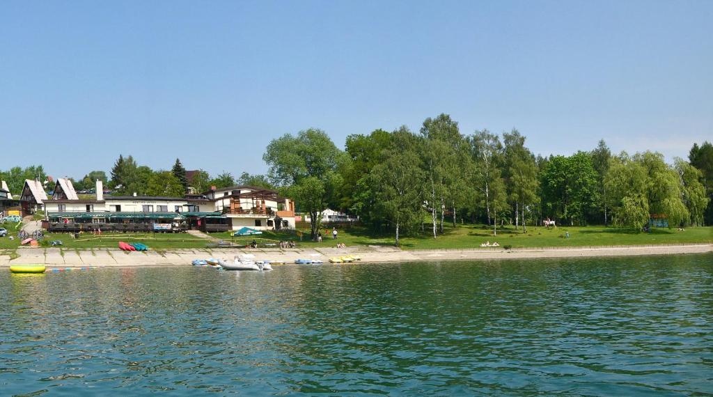 a body of water with a beach and houses at Areál Přístav in Horní Soběšovice