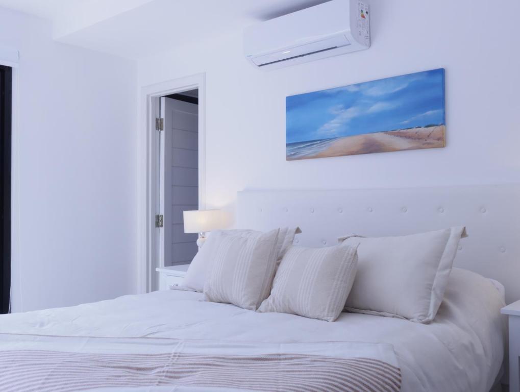 a white bedroom with a bed with white pillows at B Monoambiente en Mar del Plata a metros del mar in Mar del Plata