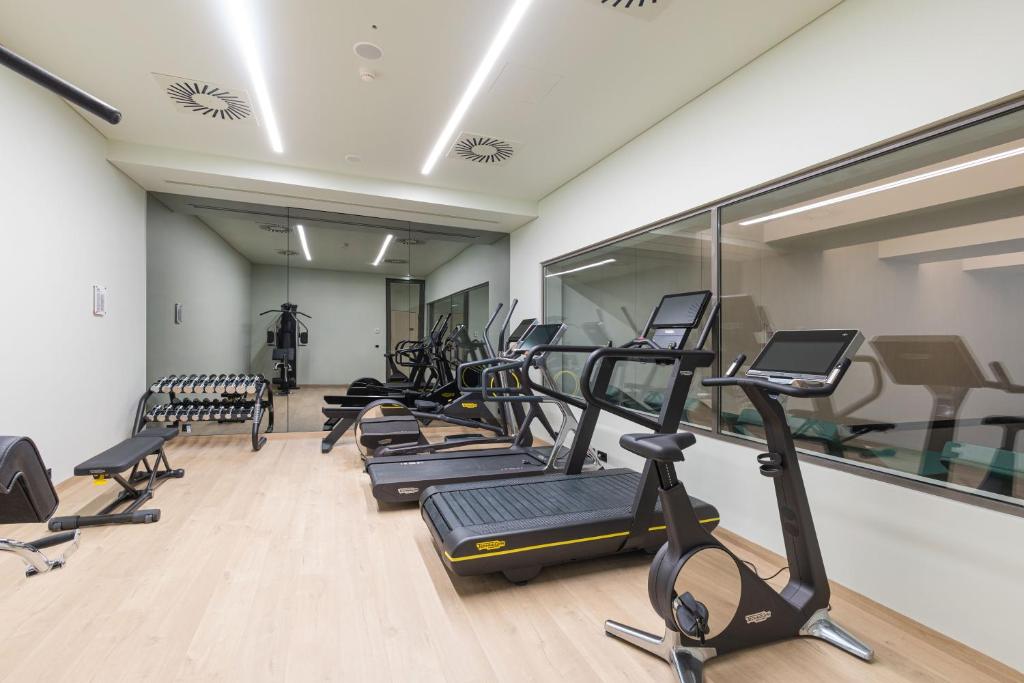 A compact, mirrored fitness room with treadmills, elliptical trainers, a bike, weights, and a cable machine.