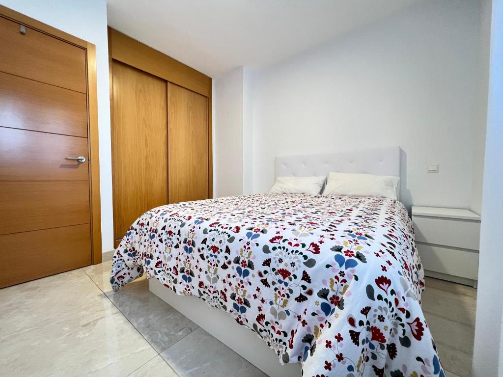 una camera bianca con un letto con un copriletto floreale. di Fabuloso apartamento completo centro ciudad a Móstoles