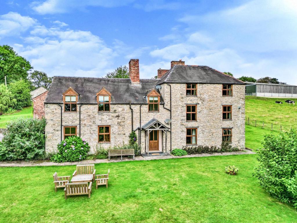 an exterior view of a large stone house with a lawn at Tywysog in Henllan