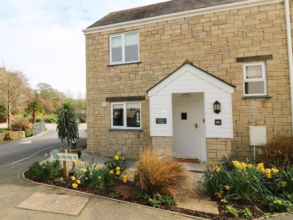 a brick house with a white door on a street at Heather's Cottage in Budock Water