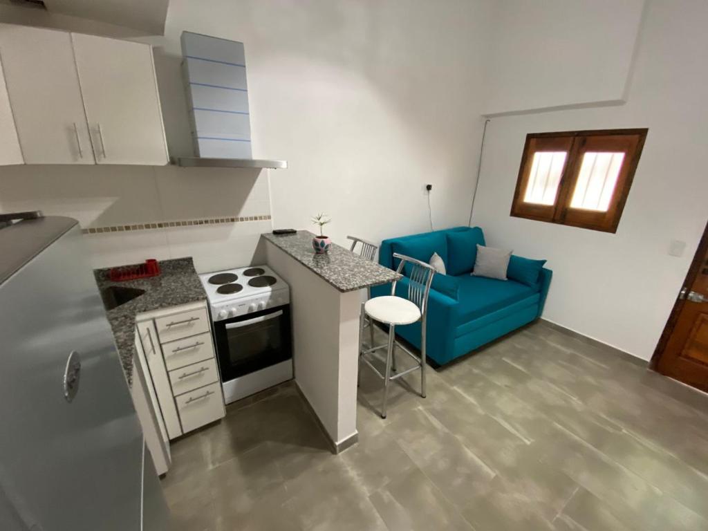 eine kleine Küche mit Herd und blauem Sofa in der Unterkunft Minicasa moderna in Castelar