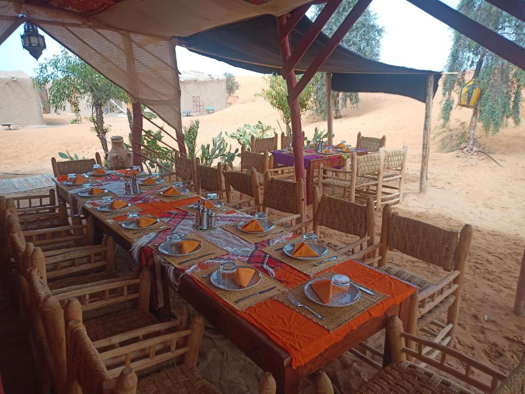 una mesa larga con platos y tazones en el desierto en SaharaTime Camp en Hassilabied