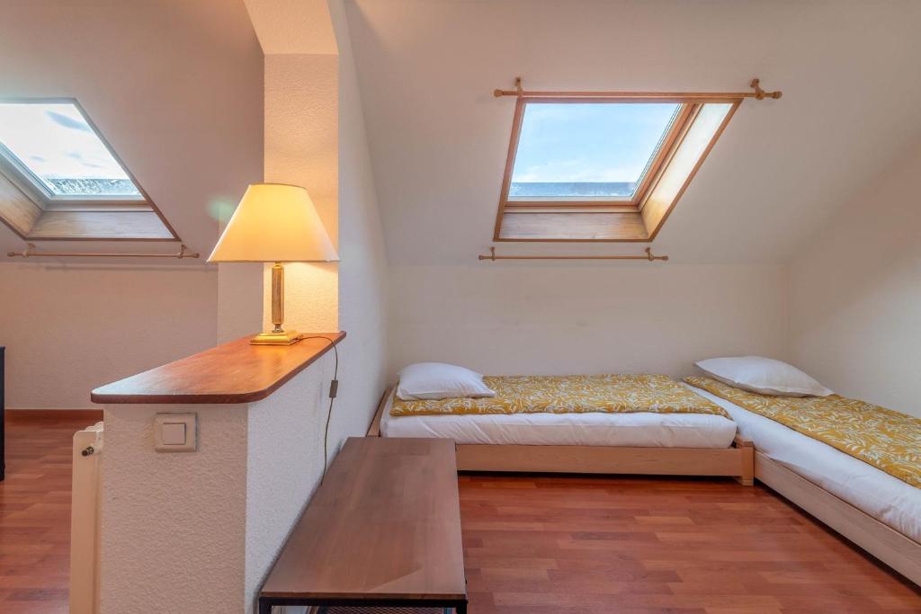 a room with two beds and a table and windows at Pleasant apartment three minutes from the center of Annecy in Annecy