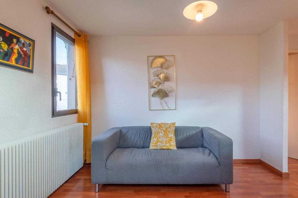 a blue couch in a living room with a window at Pleasant apartment three minutes from the center of Annecy in Annecy