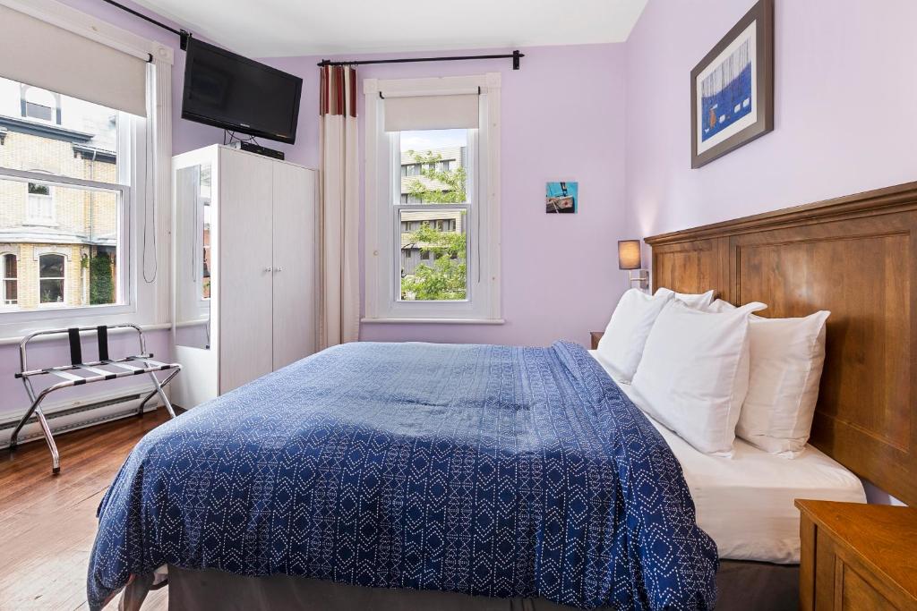 a bedroom with a bed with a blue comforter and a window at Chateau Des Tourelles in Quebec City