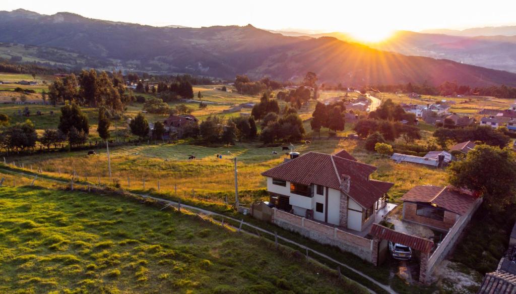 a house in a field with the sunset in the background at El Cerezo Casa de campo in Tópaga