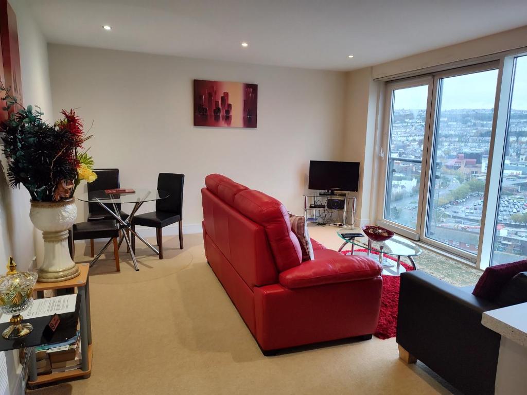 a living room with a red chair and a table at Panoramic View in Swansea