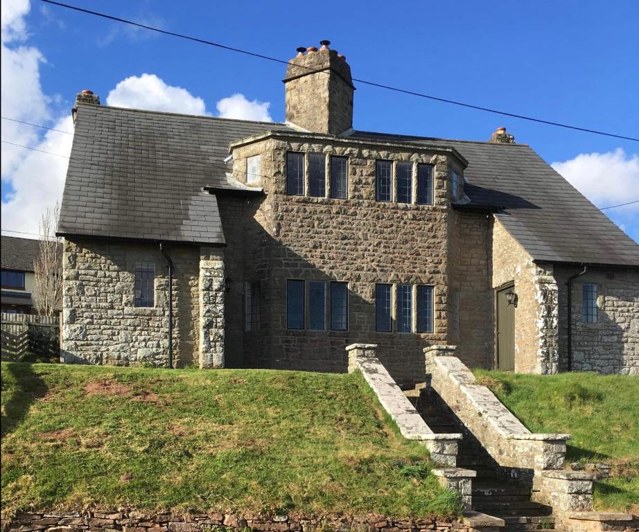 una vieja casa de piedra con escaleras delante en Cosy Arts & Crafts Cottage with stunning views, en Brecon