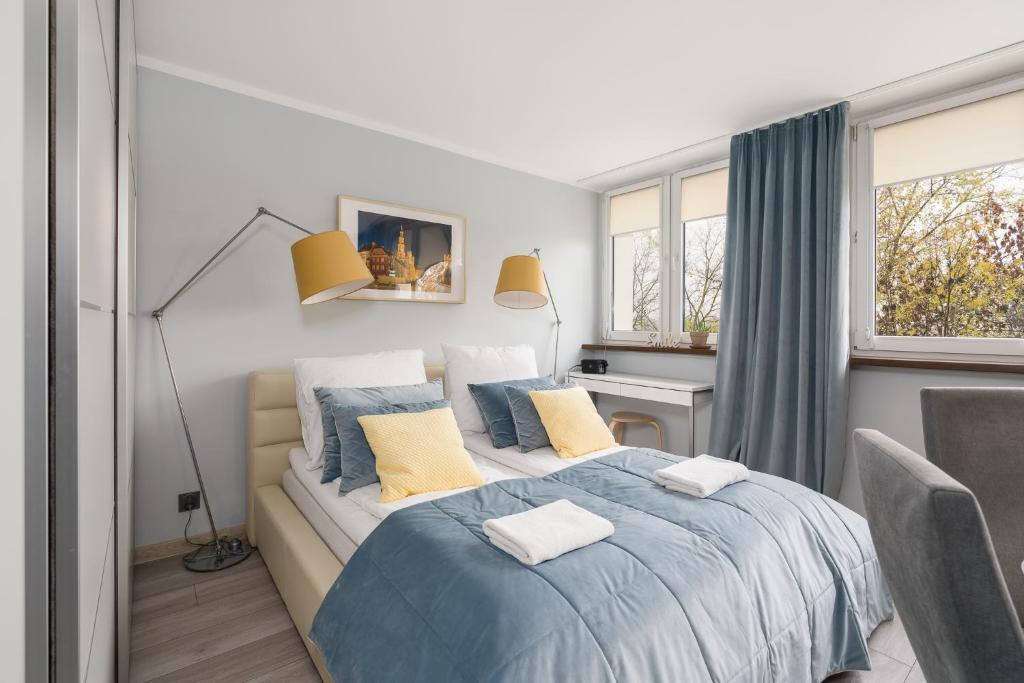 a bedroom with a bed with blue and yellow pillows at Apartament Turkusowa- z widokiem na korony drzew in Poznań