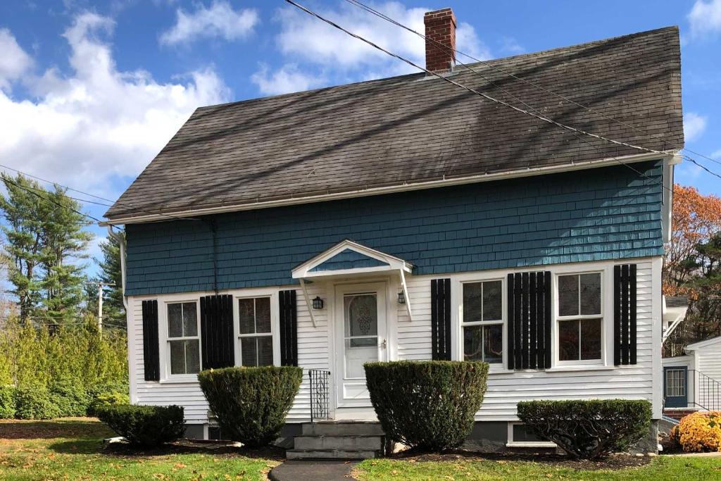 a blue and white house with bushes in front of it at Kennebunk Home with Yard Less Than 1 Mile to Dock Square! in Kennebunk