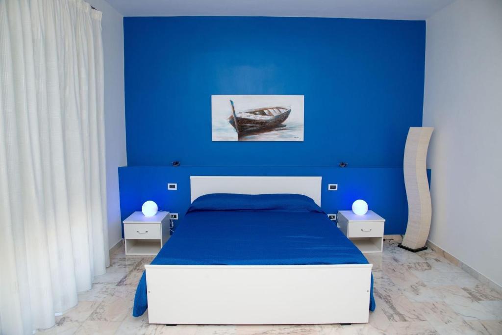 1 dormitorio azul con 1 cama y 1 barco en la pared en Note di Colore, en Sciacca