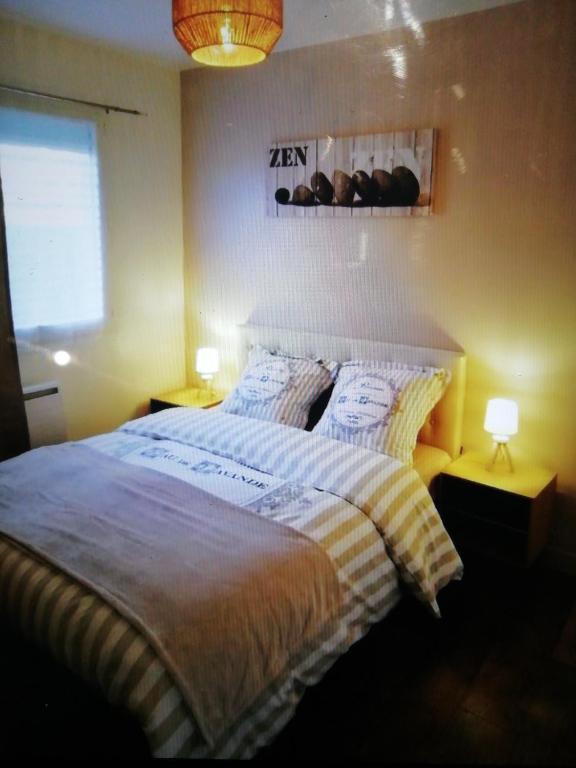 Un dormitorio con una cama con dos almohadas encima. en Bel appartement avec jardin à 50m des plages du debarquement, en Bernières-sur-Mer
