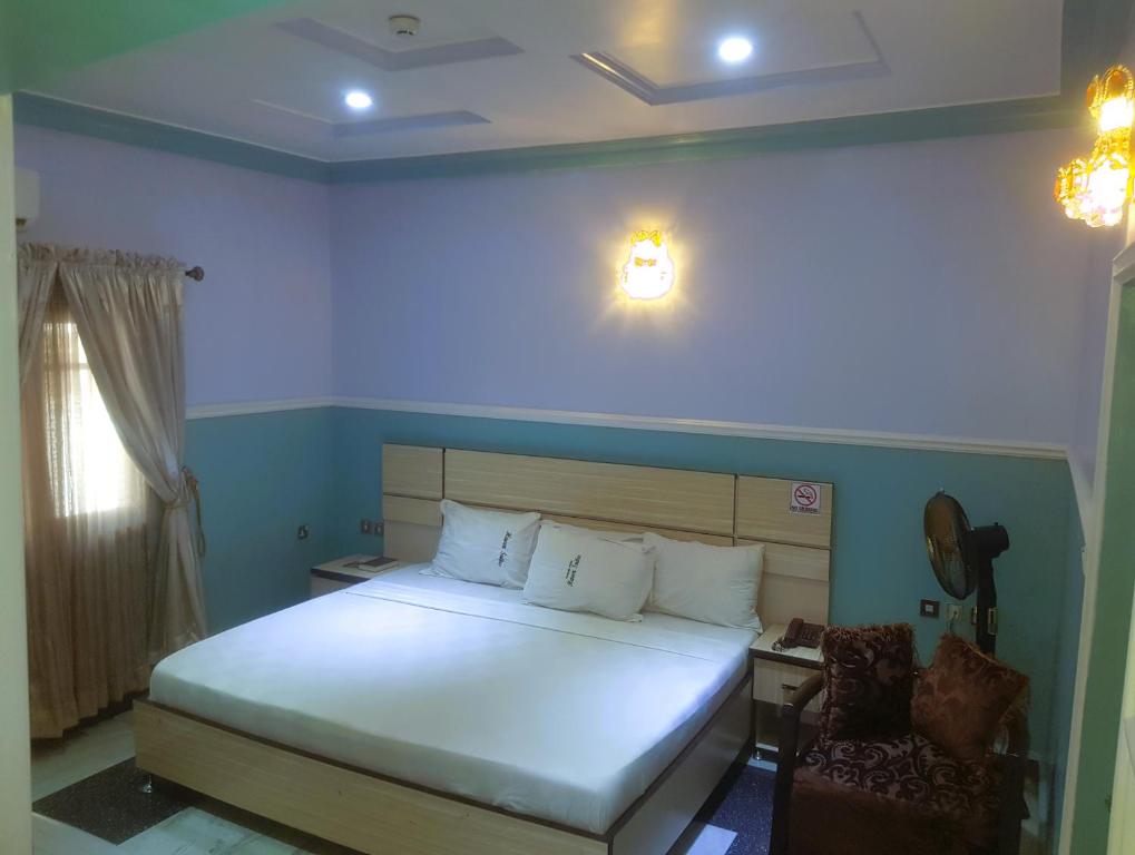 ein Schlafzimmer mit einem großen weißen Bett und einem Stuhl in der Unterkunft Haven Suites, Ikenegbu in Owerri