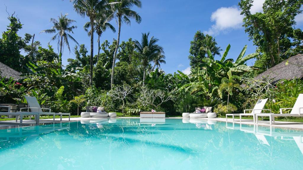 a pool at a resort with chairs and palm trees at kawayan villa siargao in General Luna