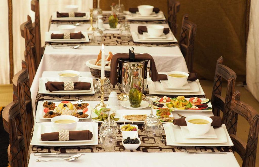 een lange tafel met borden eten erop bij camp erg chebbi luxury in Merzouga