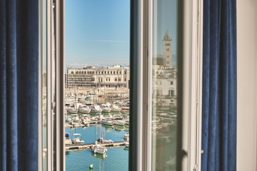 a window with a view of a harbor with boats at Michè luxury home - Appartamento vista mare a Trani in Trani