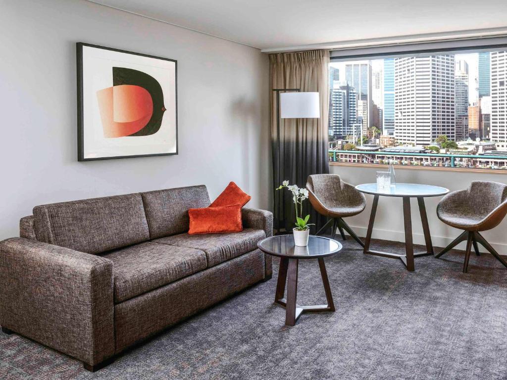 a living room with a couch and two tables at Novotel Sydney Darling Harbour in Sydney