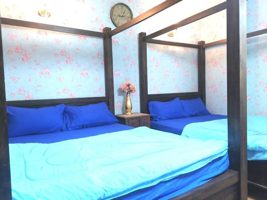 Semenyih Escapar Villa by Dan في سيمينيه: سريرين في غرفة نوم مع شراشف زرقاء وساعة