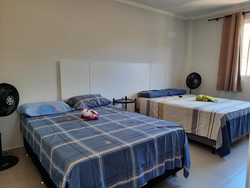 dos camas con animales de peluche sentados en una habitación en Agradável apartamento em bairro silencioso..., en Camboriú